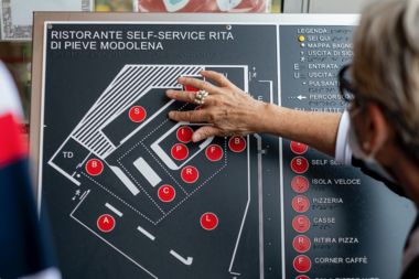 Donna con disabilit visiva tocca la mappa tattile all'ingresso del locale